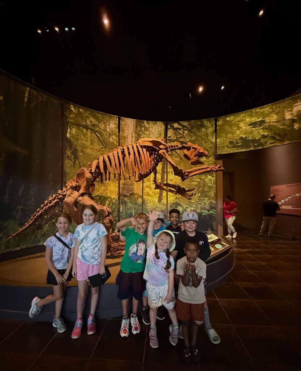 Campers posing in front of a prehistoric skeleton