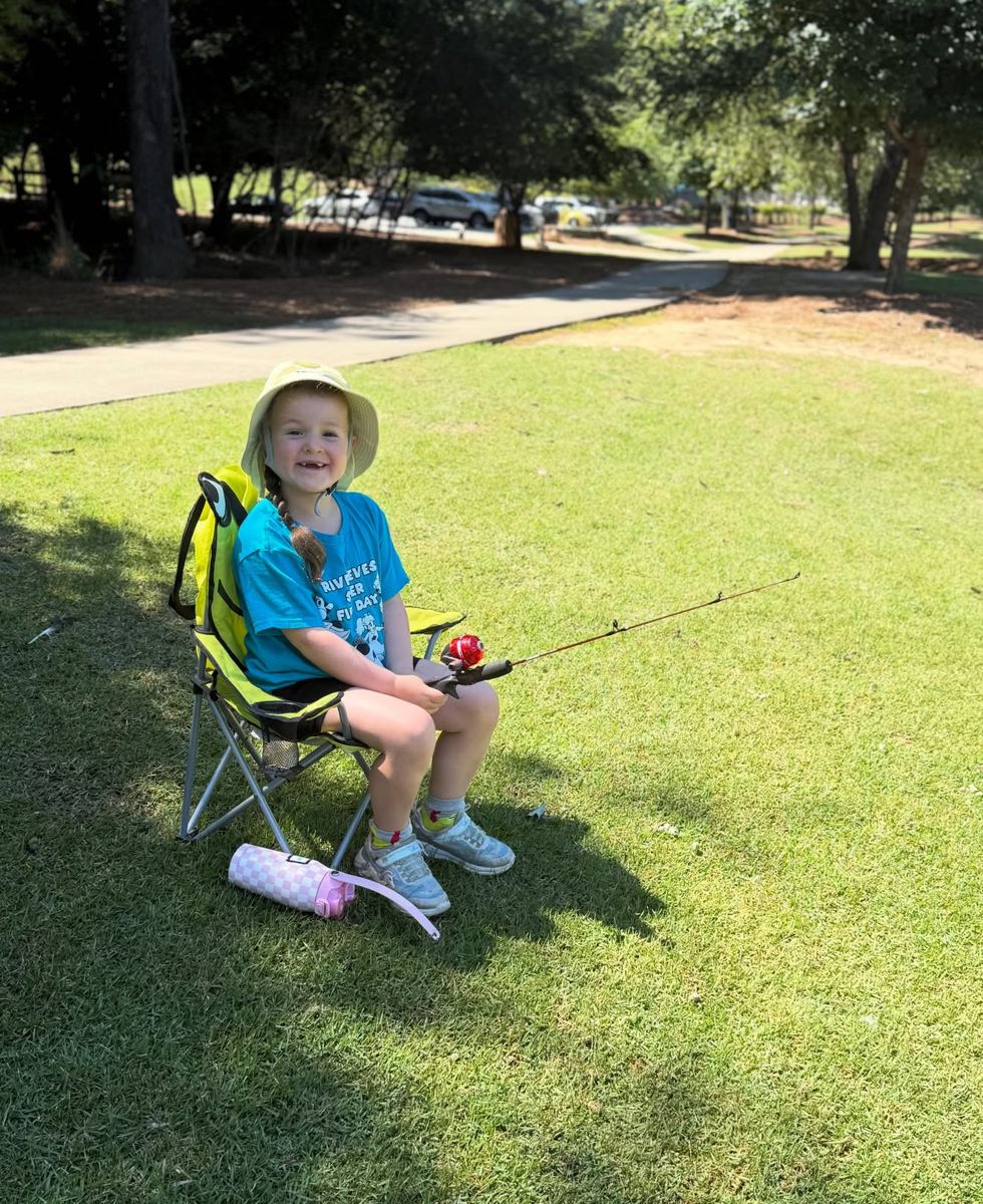 Smiling camper in a sun hat fishing from a camp chair