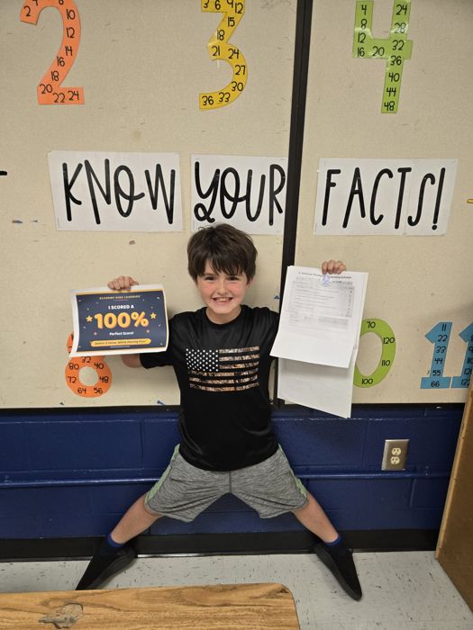 Student proudly holding a 100% score sign
