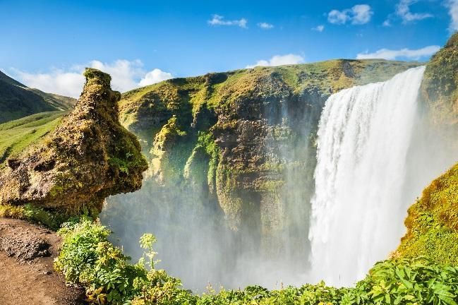 Skógafoss waterfall surrounded by green cliffs